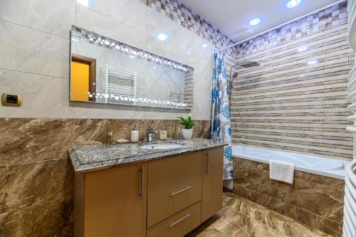 a bathroom with a sink and a tub and a mirror at JAD - Comfortable 3 Rooms Family Apartments Coresi ISARAN in Braşov