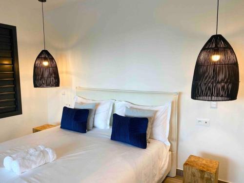una camera da letto con un letto bianco con due cuscini blu di CASA FERDI 1, logement entier avec piscine privée a Le Marin