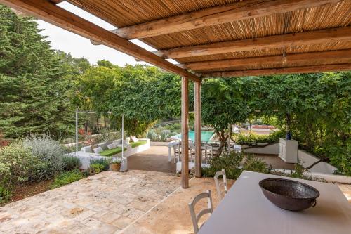 an outdoor patio with a table and a wooden pergola at Dimora Dei Semplici in Ostuni