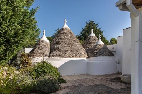 a group of five straw roofs on a white fence at Dimora Dei Semplici in Ostuni