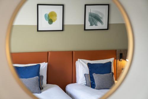 voco Edinburgh - Royal Terrace, an IHG Hotel في إدنبرة: مرآة تعكس سريرين في غرفة الفندق