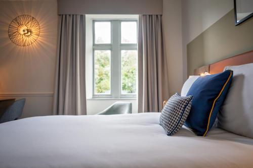 a hotel room with a bed with blue pillows and a window at voco Edinburgh - Royal Terrace, an IHG Hotel in Edinburgh