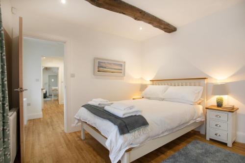 1 dormitorio con 1 cama con sábanas blancas y almohadas blancas en The Coffin Maker's Cottage, Bunny, en West Leake