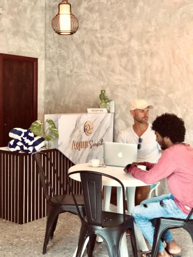 two people sitting at a table with a laptop at Aqua Sunset in Gulhi