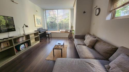 een woonkamer met een bank en een tv bij Tender grey by HolyGuest in Tel Aviv
