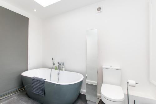 a bathroom with a bath tub and a toilet at Seaside Retreat W Garden - Beach Hut Hire in Broadstairs