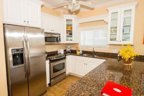 La cuisine est équipée de placards blancs et d'un réfrigérateur en acier inoxydable. dans l'établissement SANS SOUCI home, à Bradenton Beach