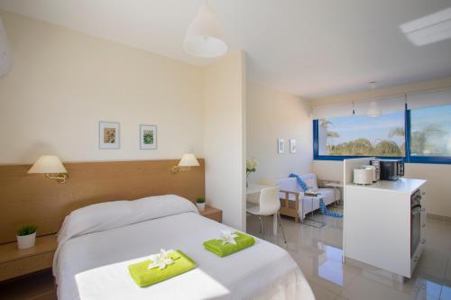 Una habitación de hotel con una cama con dos toallas verdes. en Flouressia Gardens en Protaras
