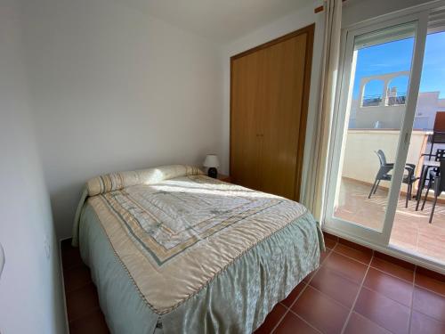 a bedroom with a bed and a large window at Adosados Palm Beach Altamar in Alcossebre