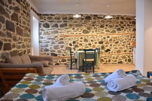 sala de estar con pared de piedra y mesa con toallas en The apricot tree studio, en Samotracia
