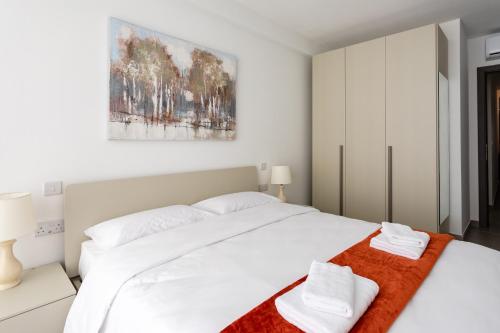 1 dormitorio con 1 cama blanca grande y 2 toallas en Gospa 58 - 1 bedroom apt en Birżebbuġa