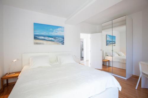 a white bedroom with a white bed and a desk at Apartment URSA in Podgora