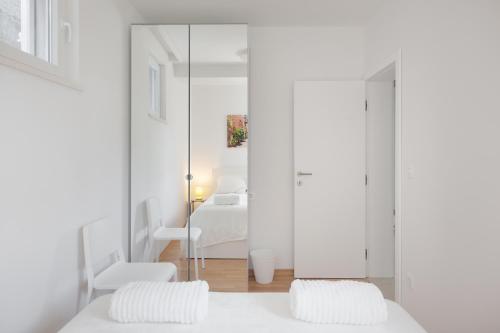 a bedroom with white walls and a bed and a mirror at Apartment URSA in Podgora