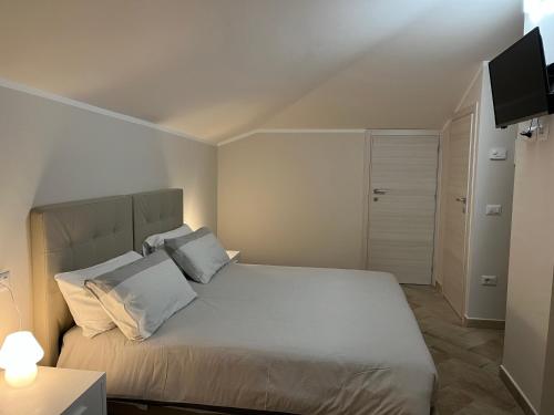 1 dormitorio con 1 cama con sábanas blancas y TV en Affittacamere Garibaldi Norcia, en Norcia
