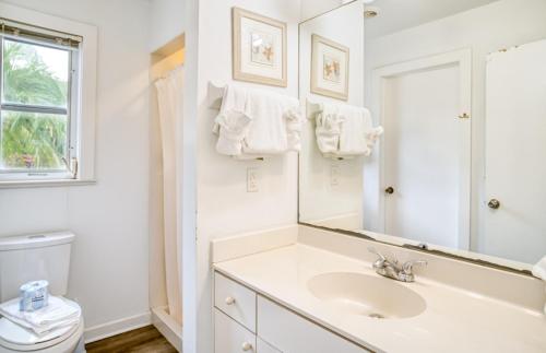 La salle de bains blanche est pourvue d'un lavabo et d'un miroir. dans l'établissement Baywatch Cottage home, à Captiva