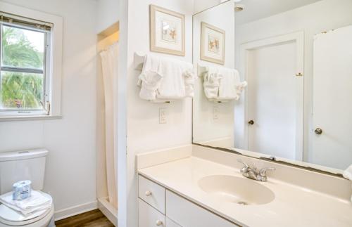 a white bathroom with a sink and a mirror at Baywatch Cottage in Captiva