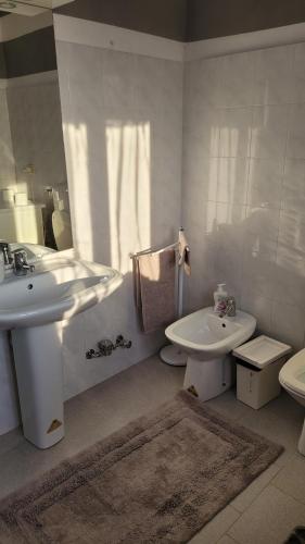 a white bathroom with a sink and a toilet at Casa vacanze in Mombarcaro