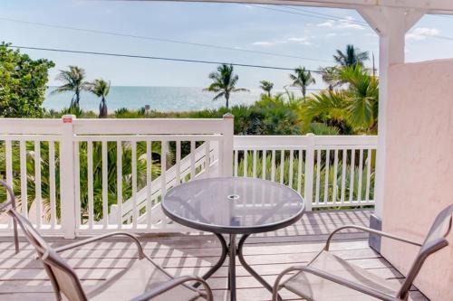 une table en verre et des chaises sur un porche avec l'océan dans l'établissement Donax condo, à Captiva