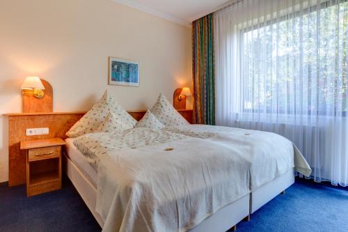 a bedroom with a bed and a large window at Der Westerwaldwirt Hotel Landhaus - Stähler in Hemmelzen