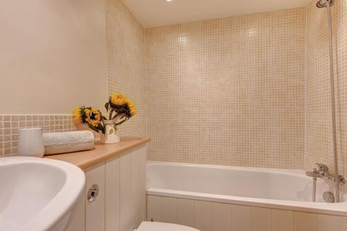 a bathroom with a tub and a toilet and a sink at April Cottage in East Rudham