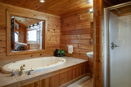 a bathroom with a tub and a sink and a mirror at A Shining Starr Beautiful MTN Views Hot Tub in Sevierville