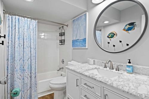 a bathroom with a sink and a toilet and a mirror at Coastal Oasis with Pool - Walk to Coligny Beach Park in Hilton Head Island