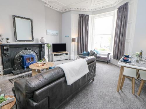 a living room with a leather couch and a fireplace at Grand View in North Shields