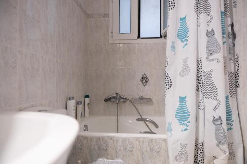 Un baño con bañera y cortina de ducha. en Despoina's Lovely Apartment, en Nauplia