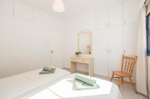 a white room with a bed and a chair at Flouressia Gardens in Protaras