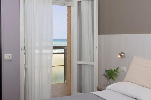 a bedroom with a bed and a view of the ocean at Bikini Tropicana Family Hotel in Lido di Savio