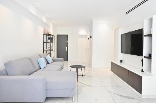 een witte woonkamer met een bank en een tv bij Delicate Lace by HolyGuest in Tel Aviv