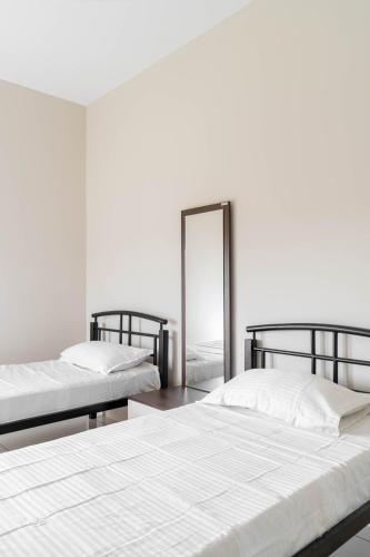 two beds in a white room with a mirror at Amminis Mansion by Doris Homes in Trichūr
