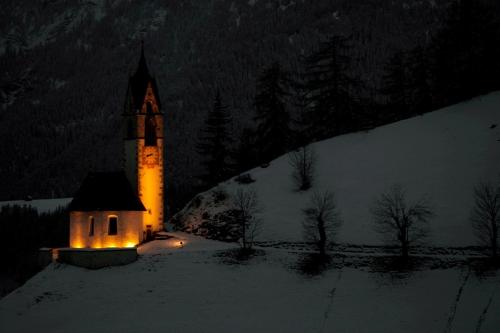a church with its lights on in the snow at night at Ciasa Raut in La Valle