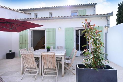 une table avec des chaises et un parasol sur une terrasse dans l'établissement Maison de vacances La Couardaise île de ré, à La Couarde-sur-Mer
