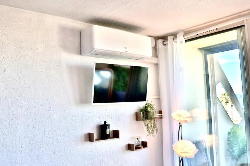 a white wall with a tv and a window at 'Cap Confession' - Naturiste - Sea View - Beach - Parking -Air Conditionaire in Cap d'Agde