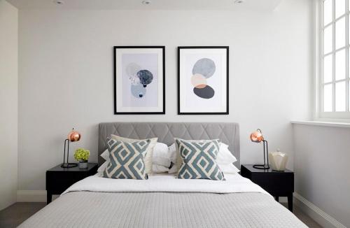 a bedroom with a bed with three pictures on the wall at Ennishmore Mews Apartment in London