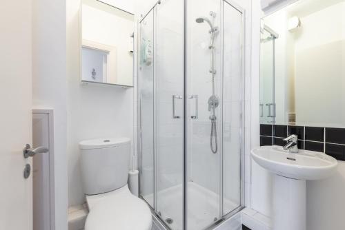 a bathroom with a shower and a toilet and a sink at Ennishmore Mews Apartment in London