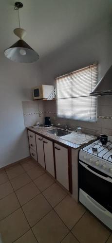 uma pequena cozinha com um fogão e um lavatório em DEPARTAMENTO LUMINOSO EUGENIO em Tandil