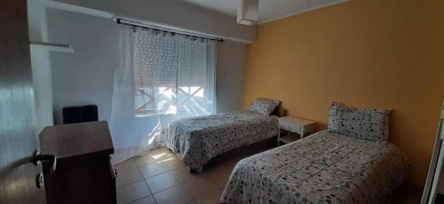 - une petite chambre avec 2 lits et une fenêtre dans l'établissement DEPARTAMENTO LUMINOSO EUGENIO, à Tandil