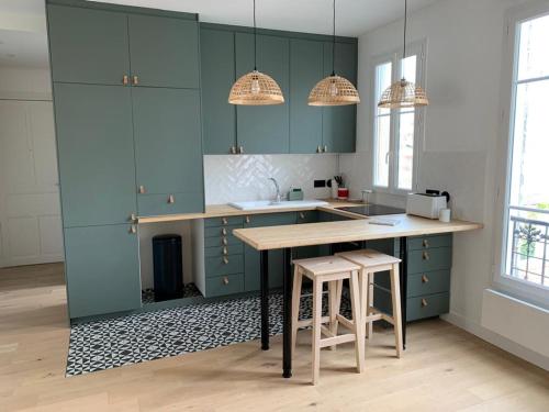 een keuken met blauwe kasten en een tafel en stoelen bij Joli appartement proche de Paris in Boulogne-Billancourt