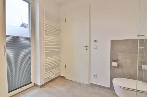 ein Bad mit einer Dusche, einem WC und einem Fenster in der Unterkunft Lüttjeod - Apartment 11 in Langeoog