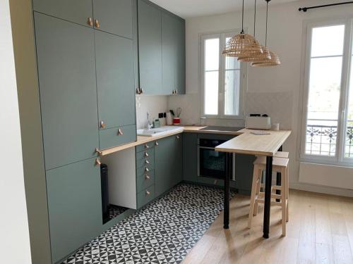 een keuken met blauwe kasten en een houten tafel bij Joli appartement proche de Paris in Boulogne-Billancourt