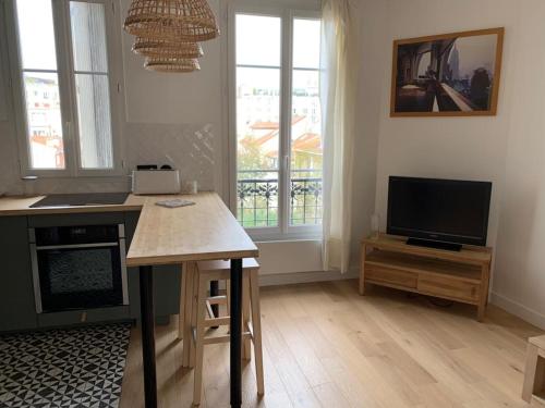 uma sala de estar com uma mesa e uma televisão em Joli appartement proche de Paris em Boulogne-Billancourt
