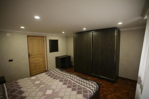 a bedroom with a bed and a wooden cabinet at Guest House Nikola in Zugdidi