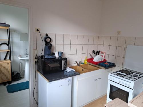 a kitchen with a microwave and a stove at Vacance solidaire appartement in La Souterraine