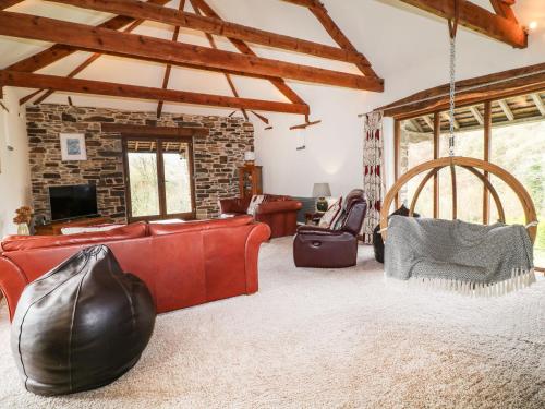 a living room with leather furniture and a stone wall at Birchenhayes in Saltash