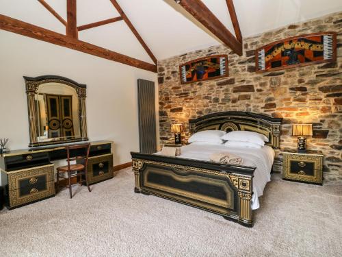 een slaapkamer met een bed en een stenen muur bij Birchenhayes in Saltash