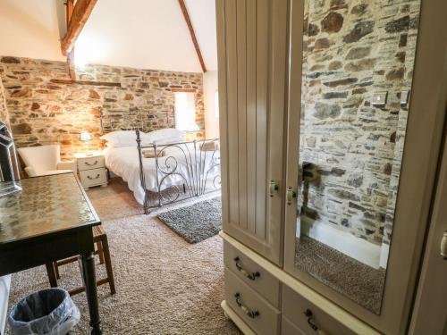 een slaapkamer met een bed en een stenen muur bij Birchenhayes in Saltash