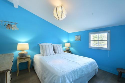a blue bedroom with a bed and a window at Maison de vacances La Couardaise île de ré in Les Prises