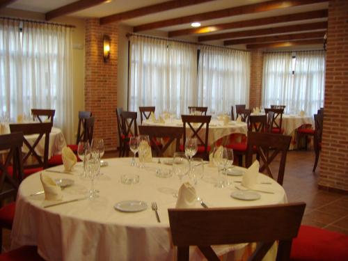 a dining room with white tables and chairs and windows at Palacio de Monfarracinos in Monfarracinos